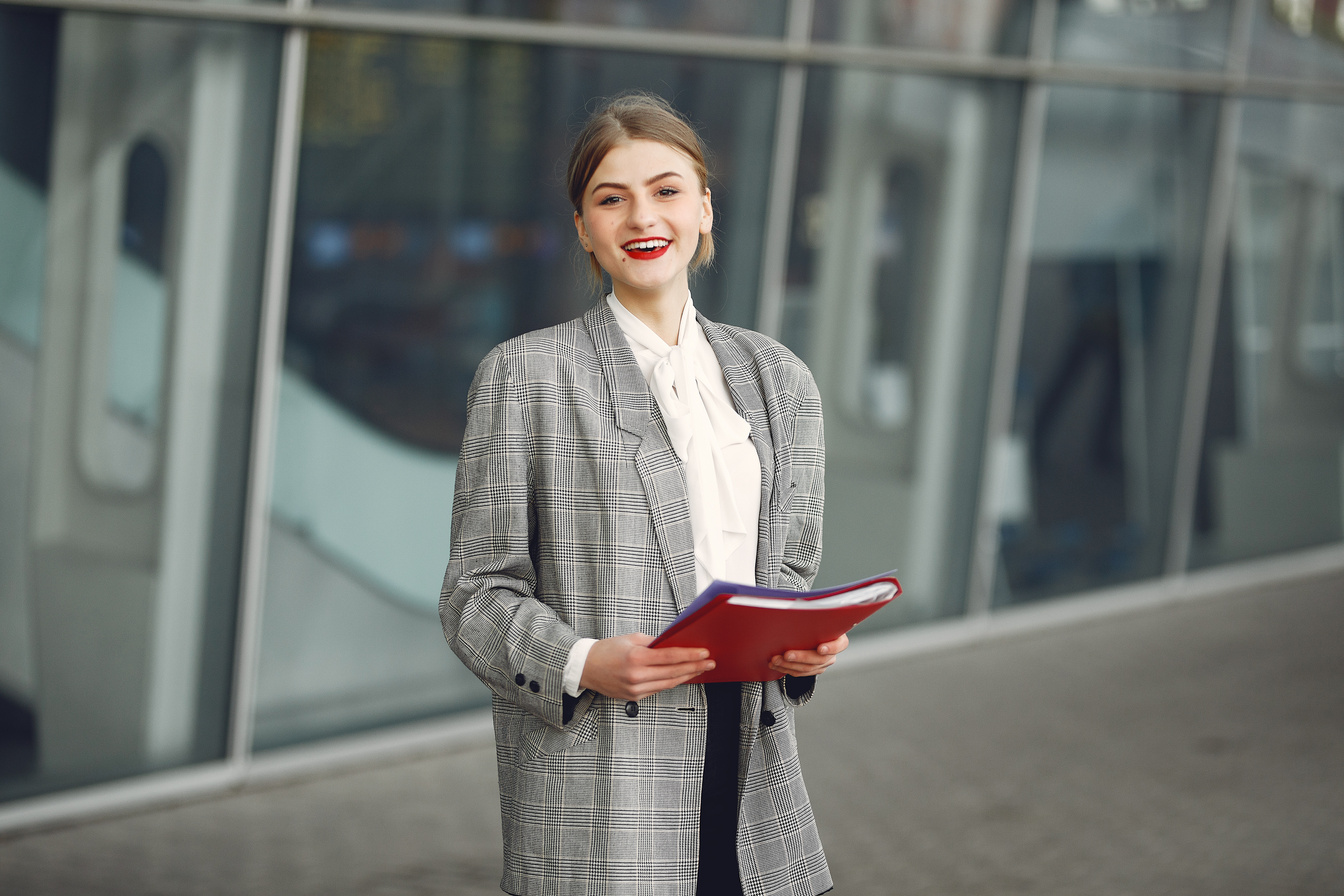 Happy female manager with papers near office building