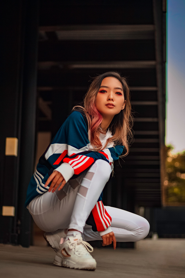 Woman in Blue, White and Red Jacket and White Pants Squatting on Floor
